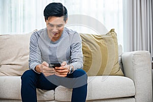 middle aged man relaxing sitting on sofa using smart mobile phone at home