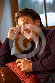 Middle Aged Man Relaxing On Sofa Drinking Whisky