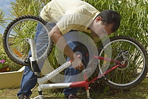 Middle-aged man repairing a bicycle.
