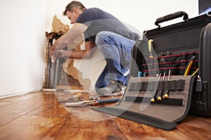 Middle aged man repairing burst pipe,plumbing, focus on foreground