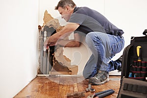 Middle aged man repairing burst water pipe