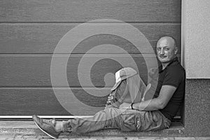 A middle-aged man is resting on the sidewalk. Portrait of caucasian bald man, outdoors. . Black and white