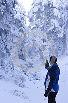 A middle-aged man searches for wifi signal on a snowy mountain. wifi connection in deep nature