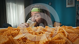 A middle aged man is shown in a close up shot with a glass of beer and chips. It is shot with macro photography. Looking