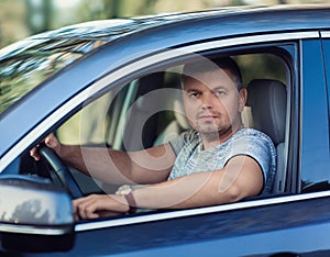 A middle-aged man sits in a car. Dear beautiful car. The man is calm and confident.