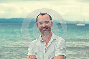 Middle aged man smiling no teeth by the beach in summer