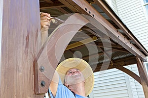 Middle-aged man staining woodwork on a gazebo