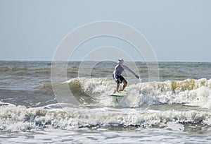 Middle aged man surfs on a longboard in the Atlantic