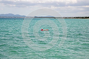 A middle aged man swimming and laying down on a pool inflatable lilo in the ocean off the coast of Majorca in Spain