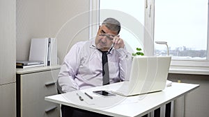 A middle-aged man is tired from working at the computer and yawns