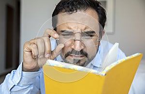 Middle aged man trying fix his glasses to see
