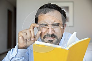 Middle aged man trying fix his glasses to see