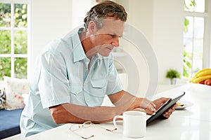 Middle Aged Man Using Digital Tablet Over Breakfast