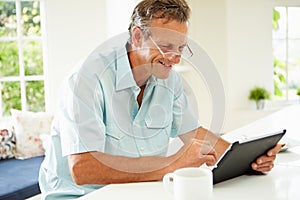 Middle Aged Man Using Digital Tablet Over Breakfast