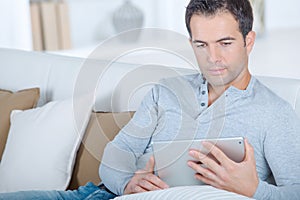 Middle-aged man using digital tablet on sofa