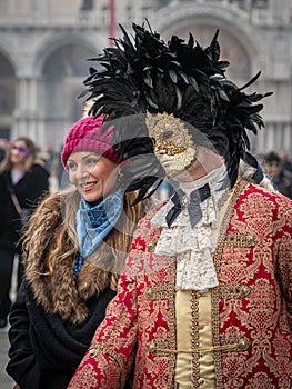 A middle-aged man in a vintage costume with a lace collar, wearing a carnival mask