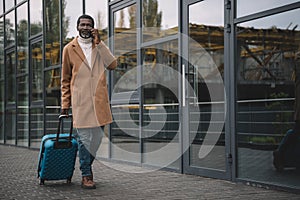 Middle aged man walking on a street with a wheeled bag and talking