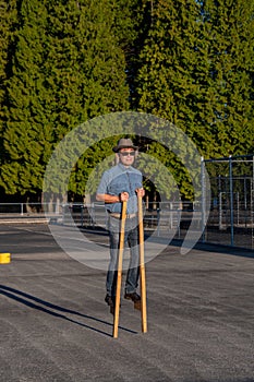 A middle-aged man walking on wooden stilts.