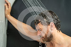 Middle aged man washing hair in bath. Guy bathing shower head in bathtub. Face in foam in shower. Bathing man taking