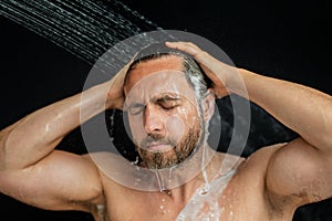 Middle aged man washing hair in bath. Guy bathing shower head in bathtub. Face in foam in shower. Bathing man taking