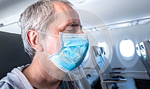 Middle aged man wearing a face mask sitting in an empty airplane