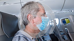 Middle aged man wearing a face mask sitting in an empty airplane