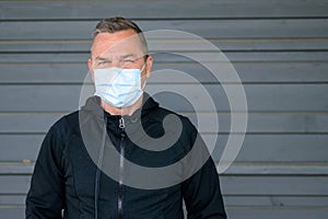 Middle-aged man wearing a face mask staring thoughtfully at camera