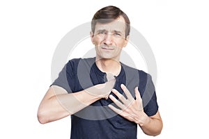 A middle-aged man on a white background with a face that feels pain is held with two hands on the heart. A man suffers from pain