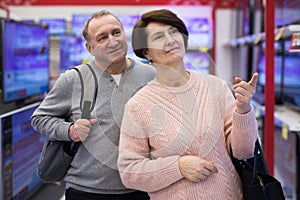 Middle aged man and woman choosing TV in electronic store