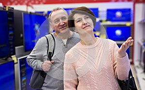 Middle aged man and woman choosing TV in electronic store