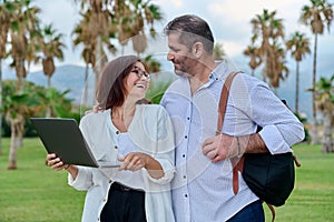 Middle-aged man and woman looking into the laptop screen outdoors