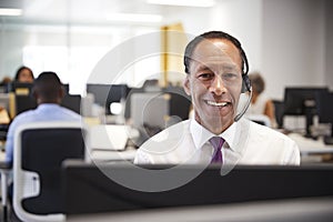 Middle aged man working at computer with headset in office