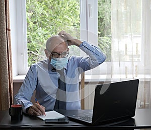 Middle-aged man works on laptop at home, hostility of emotions