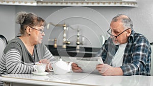 Middle aged mature couple talking debating during breakfast at white kitchen medium shot