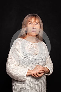 Middle aged mature woman smiling and standing against black studio wall background