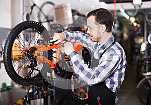 Middle-aged mechanic is working on master bicycle assembly