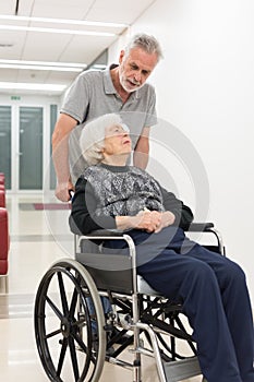 Middle aged man helping and taking to elderly 95 years old woman sitting in the wheelchair. photo