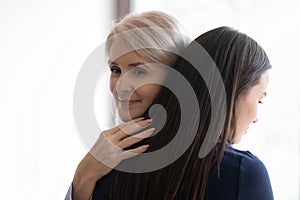 Middle-aged mom and adult daughter hug making peace