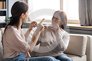 Middle aged mother and adult daughter speaking sign language