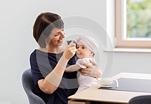 Middle-aged mother feeding baby daughter at home