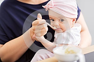 Middle-aged mother feeding baby daughter at home