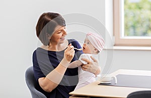 Middle-aged mother feeding baby daughter at home