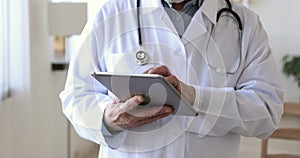 Middle aged older male doctor holding digital computer tablet.