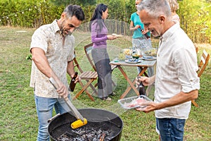 Middle-aged people around the barbecue smiling happy and laughing together. Joy concept.