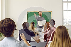 Middle aged professor lector is showing on student in class for answer the question. photo