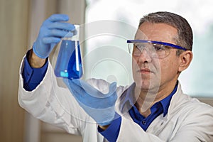Middle Aged Scientist Examining a Beaker of Blue Fluid