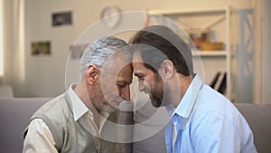 Middle-aged and senior males touching foreheads good relations between relatives