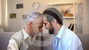 Middle-aged and senior males touching foreheads good relations between relatives