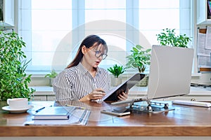 Middle-aged serious woman working at computer laptop in home office