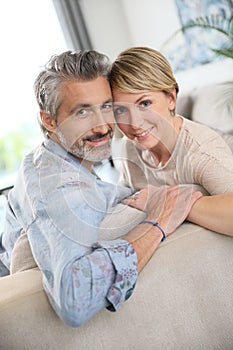 Middle-aged smiling couple on sofa